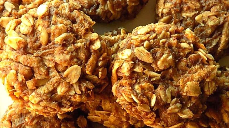 Stacked apple oatmeal cookies with a glass of milk in the background.