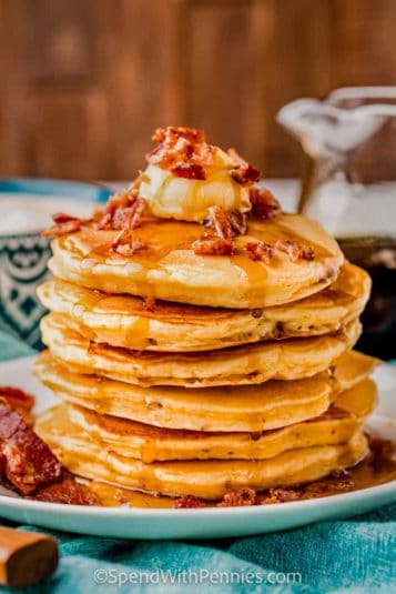 Pile of Bacon Pancakes with syrup and bacon on top.