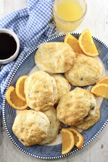Air Fryer Sausage Biscuits on a platter with slices of fresh oranges, coffee and juice.