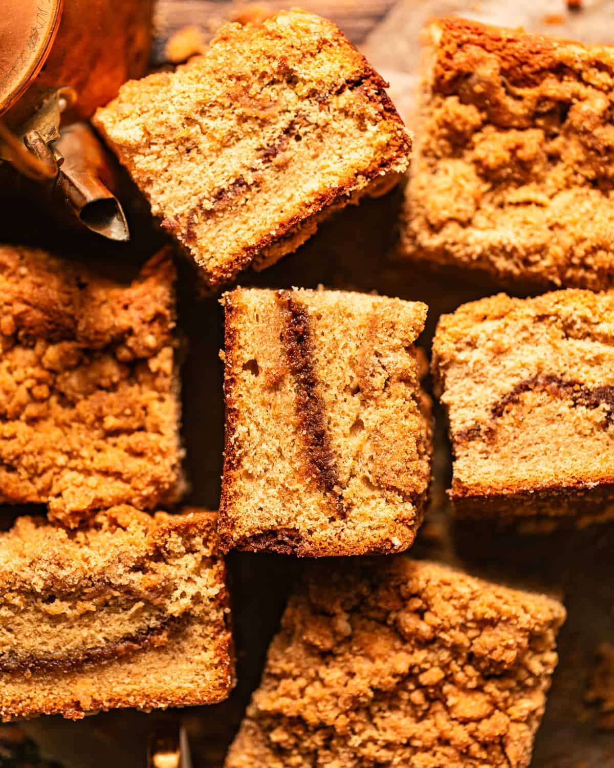 Cardamom coffee cake cut into squares and scattered about on a piece of parchment paper.