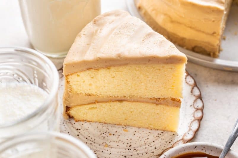 A slice of caramel cake next to the cake.