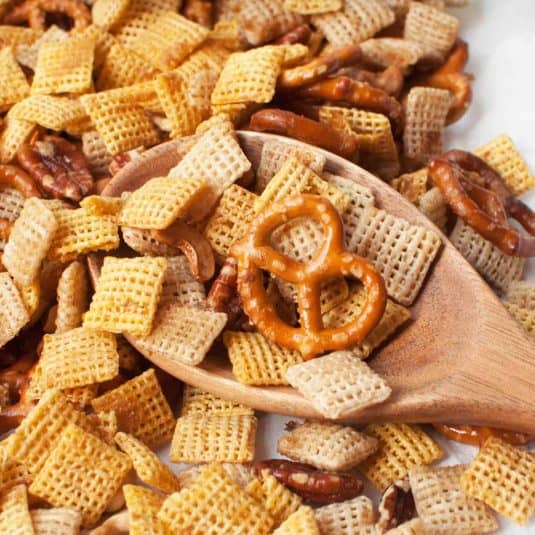 A spoon scooping garlic chex mix.