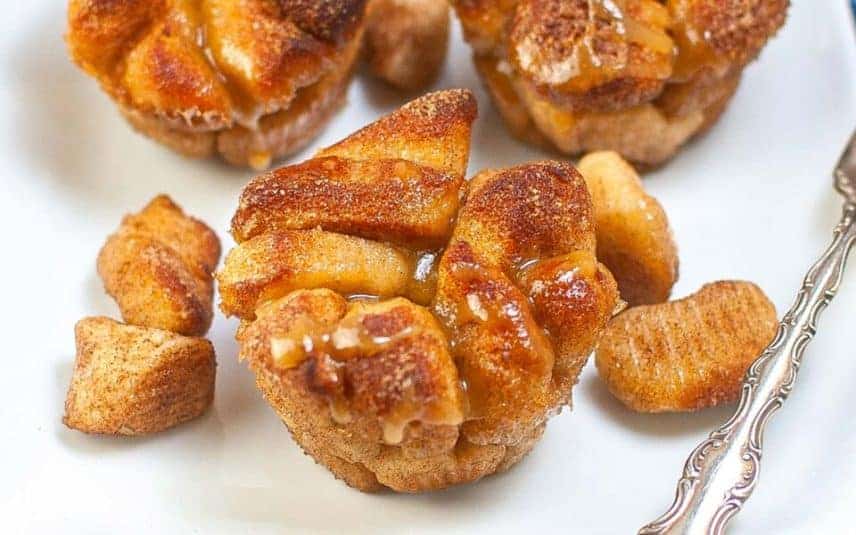 Sweet, glazed monkey bread pieces served in a white bowl, drizzled with icing.