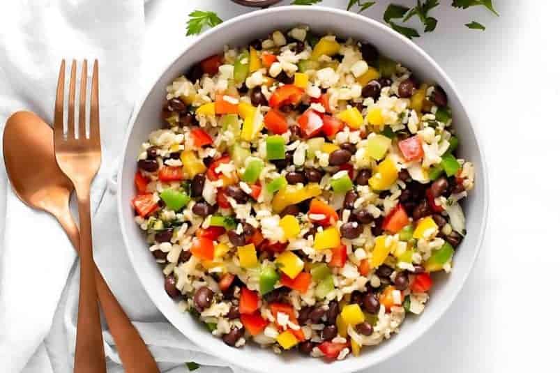 A bowl of festive Mexican rice salad with fresh veggies and cilantro.