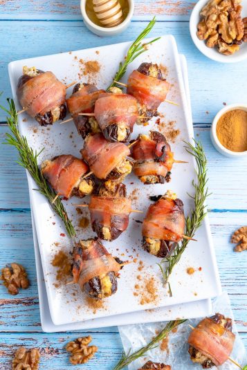 Overhead of Bacon Wrapped Dates on white platter with herbs.