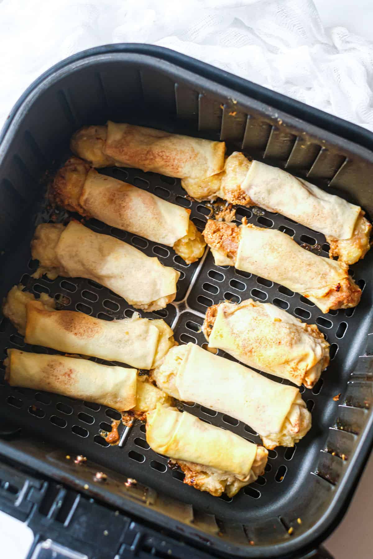 Peanut butter banana spring rolls in an air fryer basket.