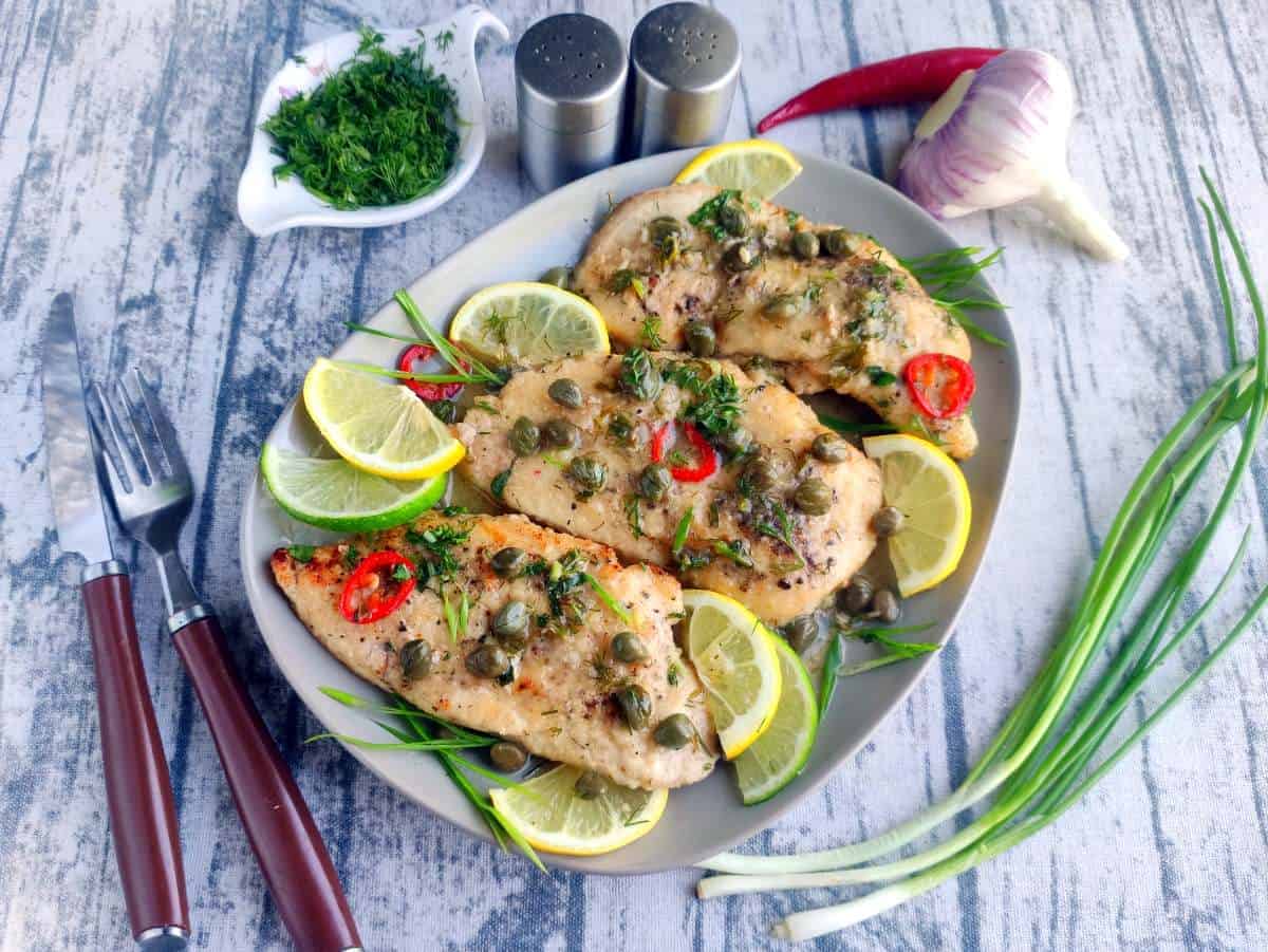 Chicken Caprese with tomato and basil on a blue plate.