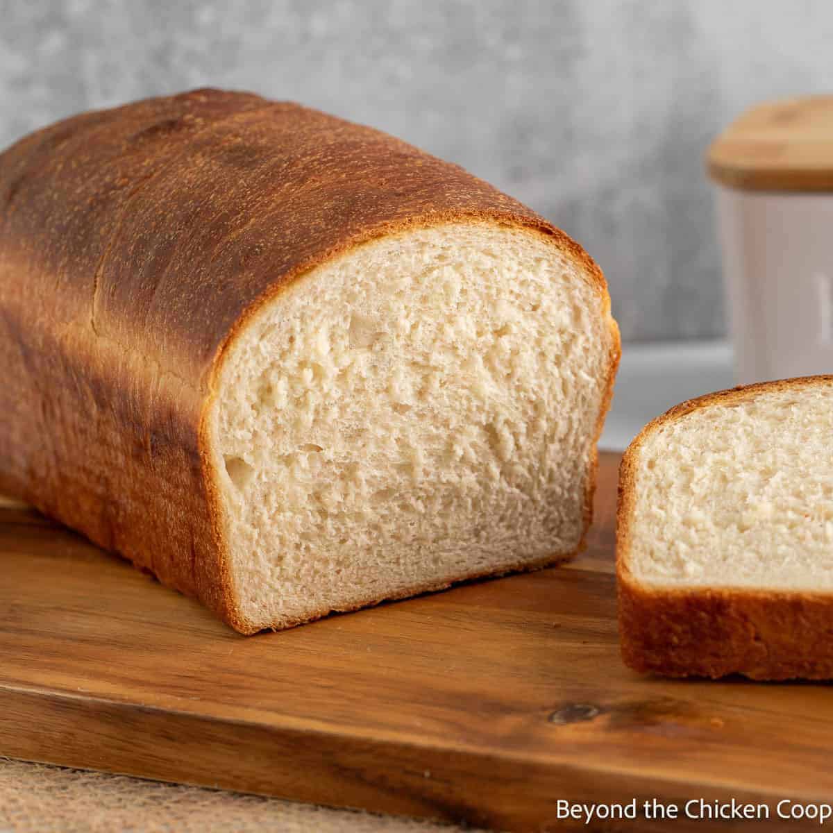 A loaf of homemade white bread on a wooden cutting board.