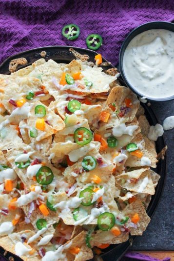 Jalapeño Popper Nachos Topped with Garlic Cream in Black Plate.