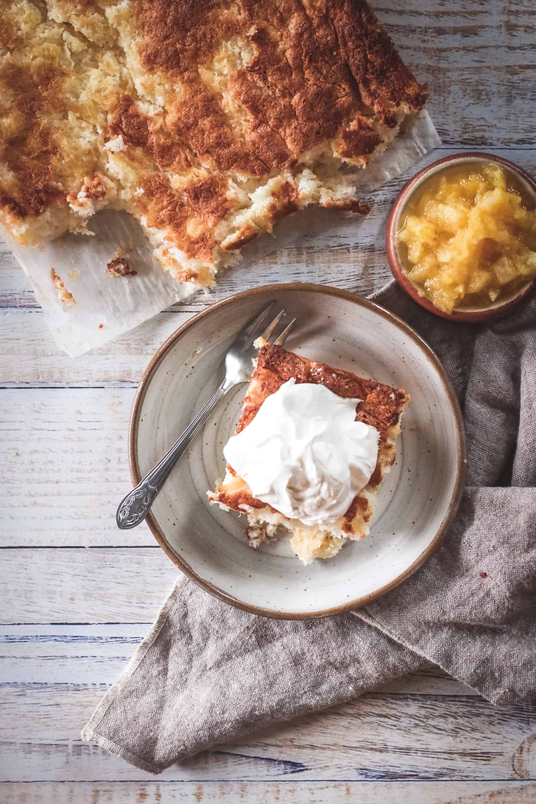 Overhead view of a piece of pineapple cake with whip cream on top.