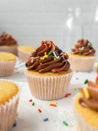 Vanilla Cupcakes with Chocolate Frosting and rainbow sprinkles.