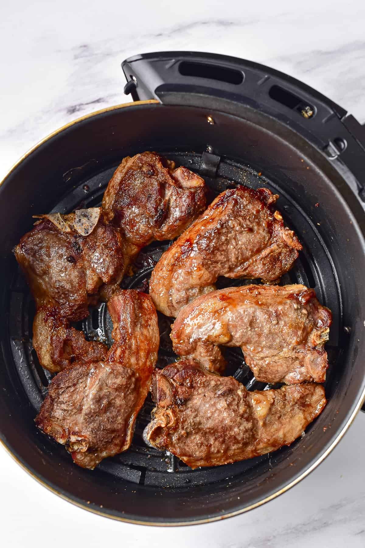 Air fryer lamb chops in air fryer basket.