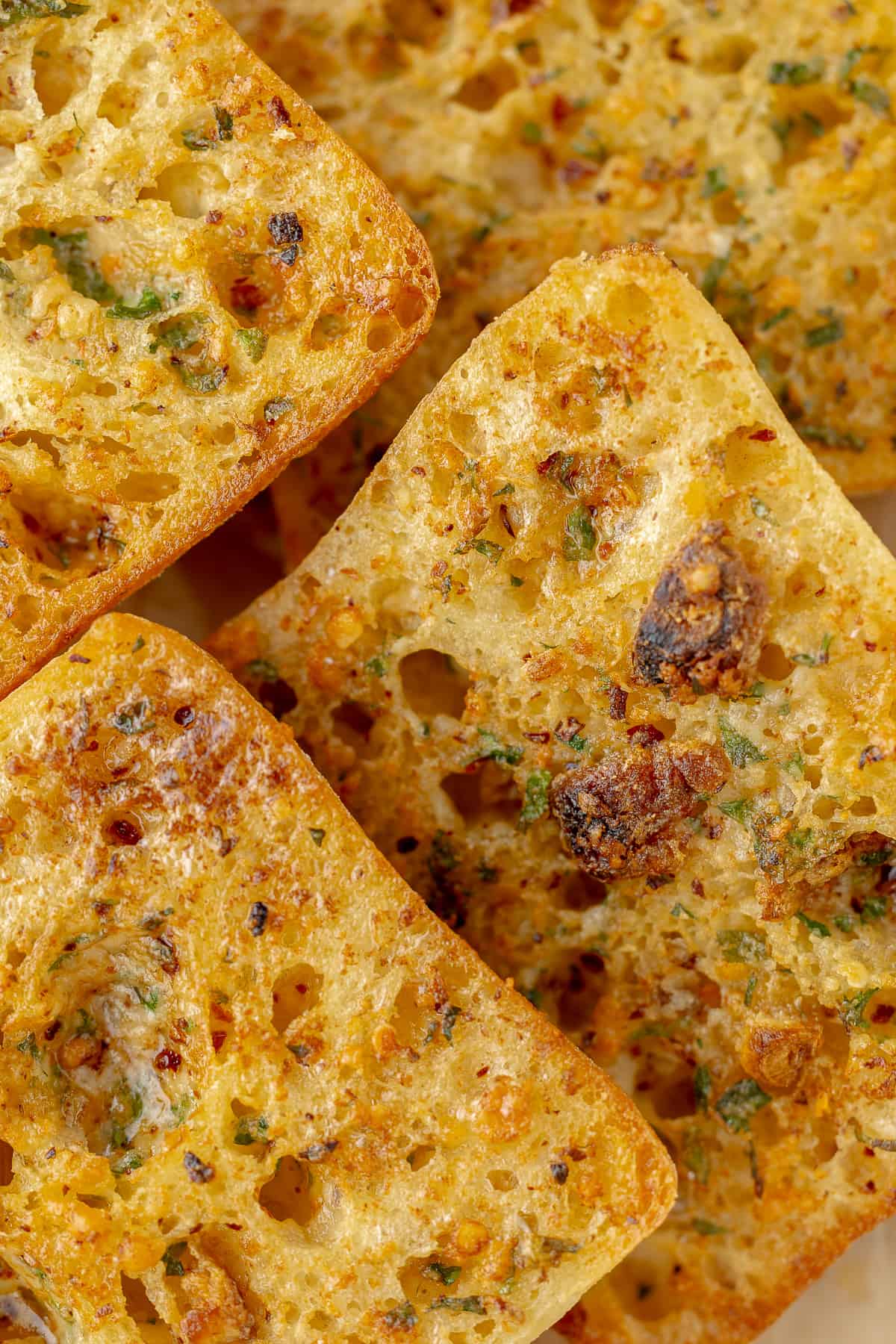 Toasted garlic bread arranged on parchment paper.