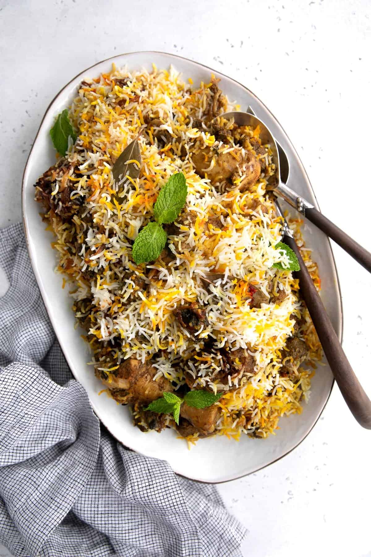 Large platter filled with cooked lamb and chicken biryani recipe.