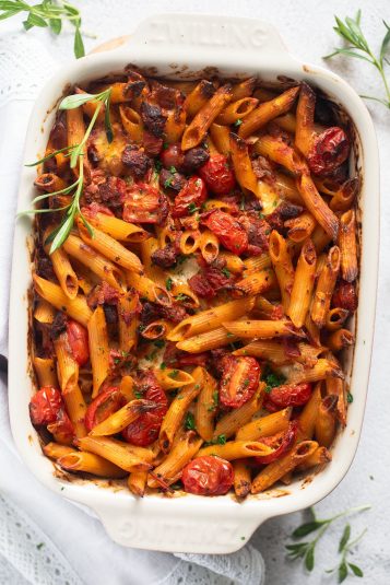 Baking dish full of golden brown pasta and chorizo bake with tomatoes and mozzarella.