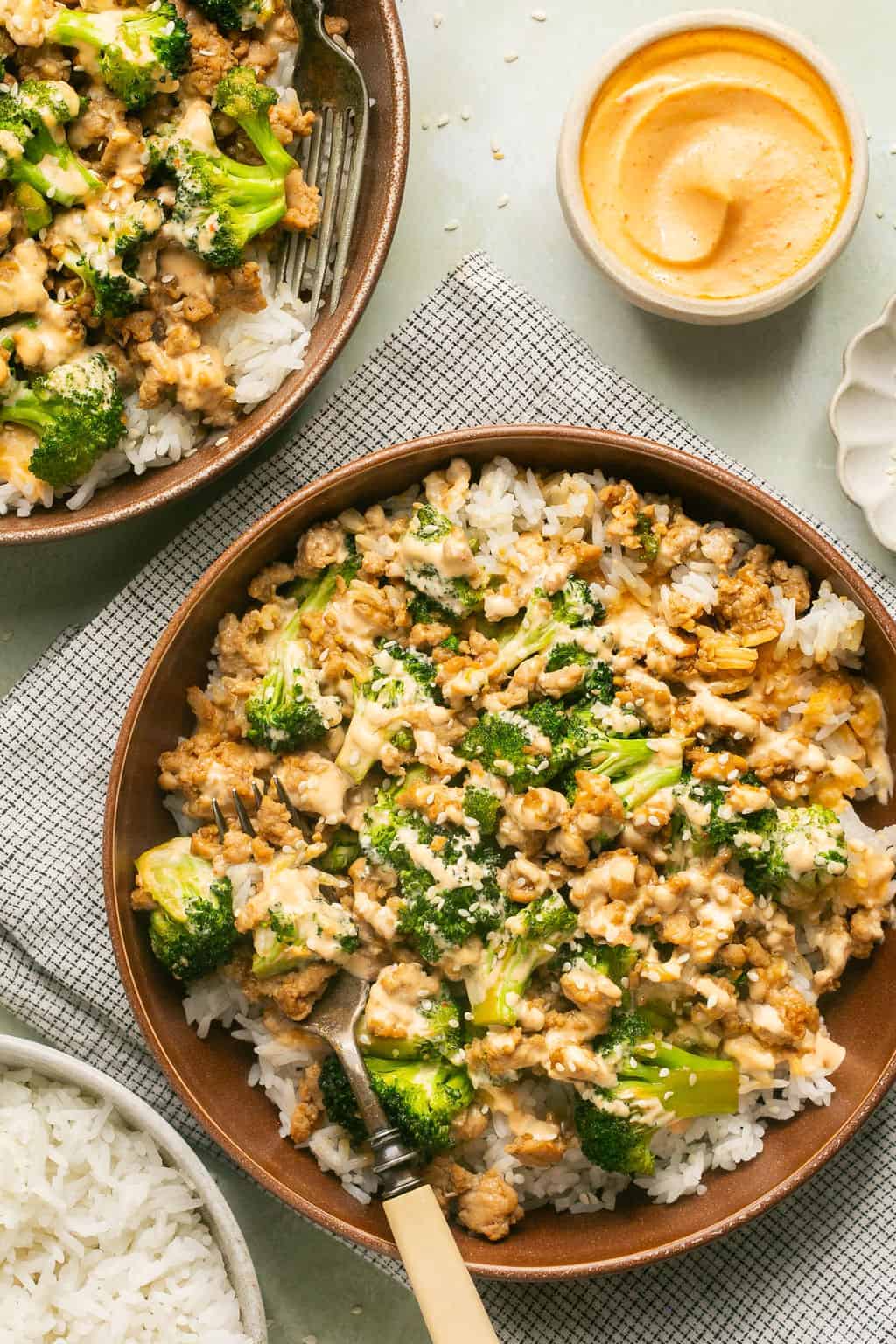 Asian ground chicken rice bowls with a fork and side of sriracha mayo.