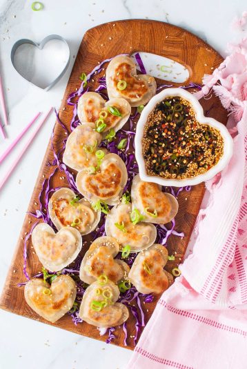 Heart-shaped dumplings on a wooden cutting board.