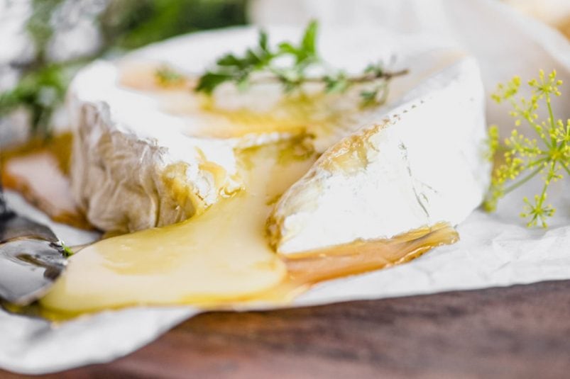 Cutting into a baked Brie topped with honey.