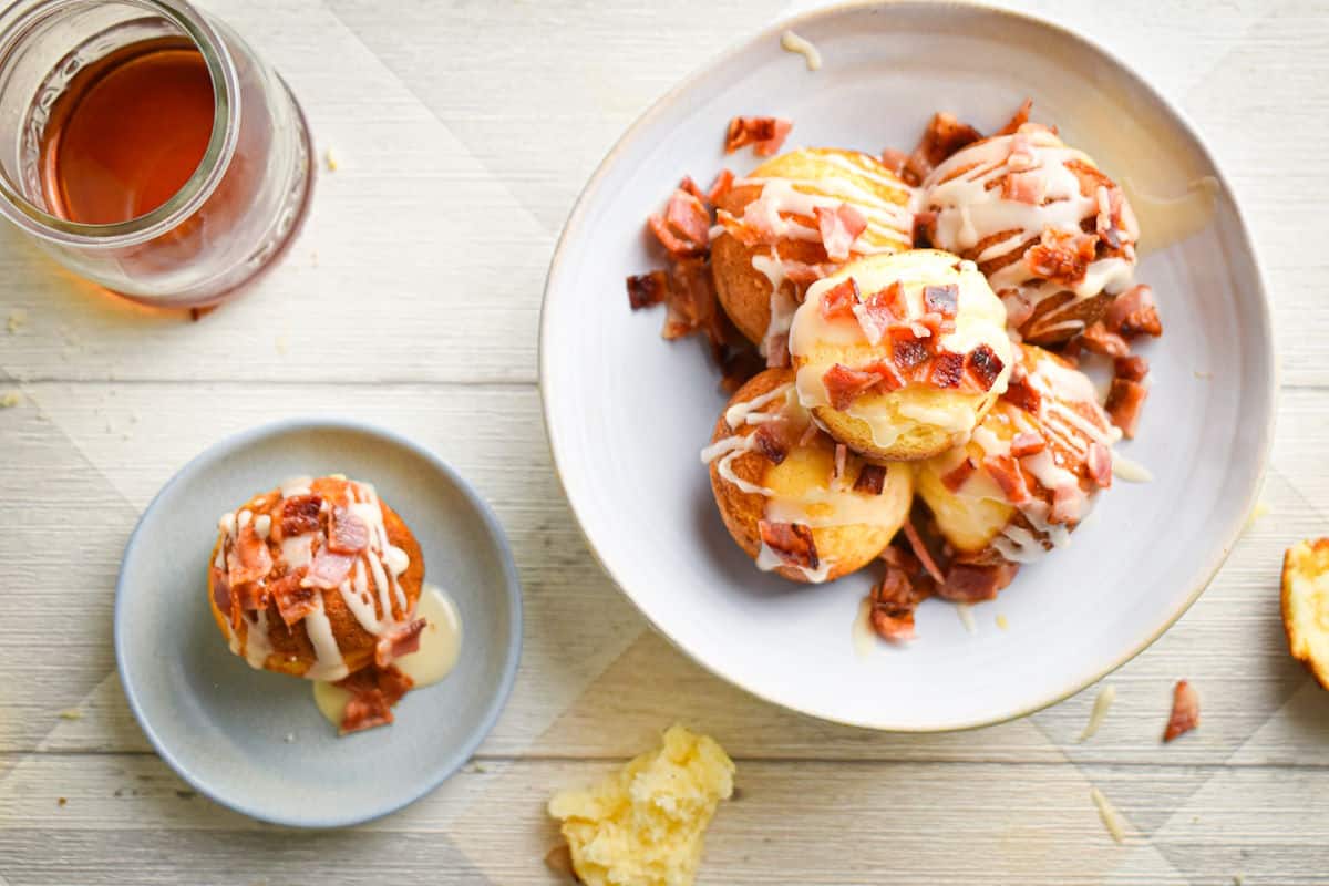 Maple bacon cake balls on plates with a jar of maple syrup on the side.