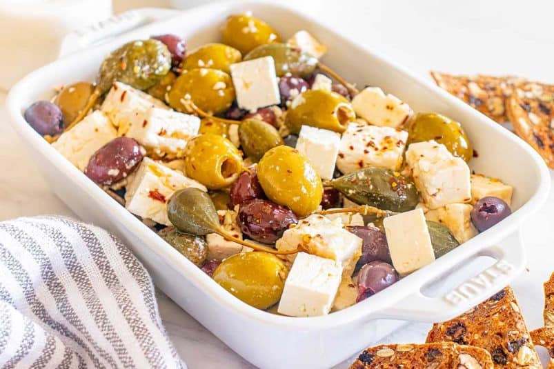 A dish with a marinated olive and feta appetizer.