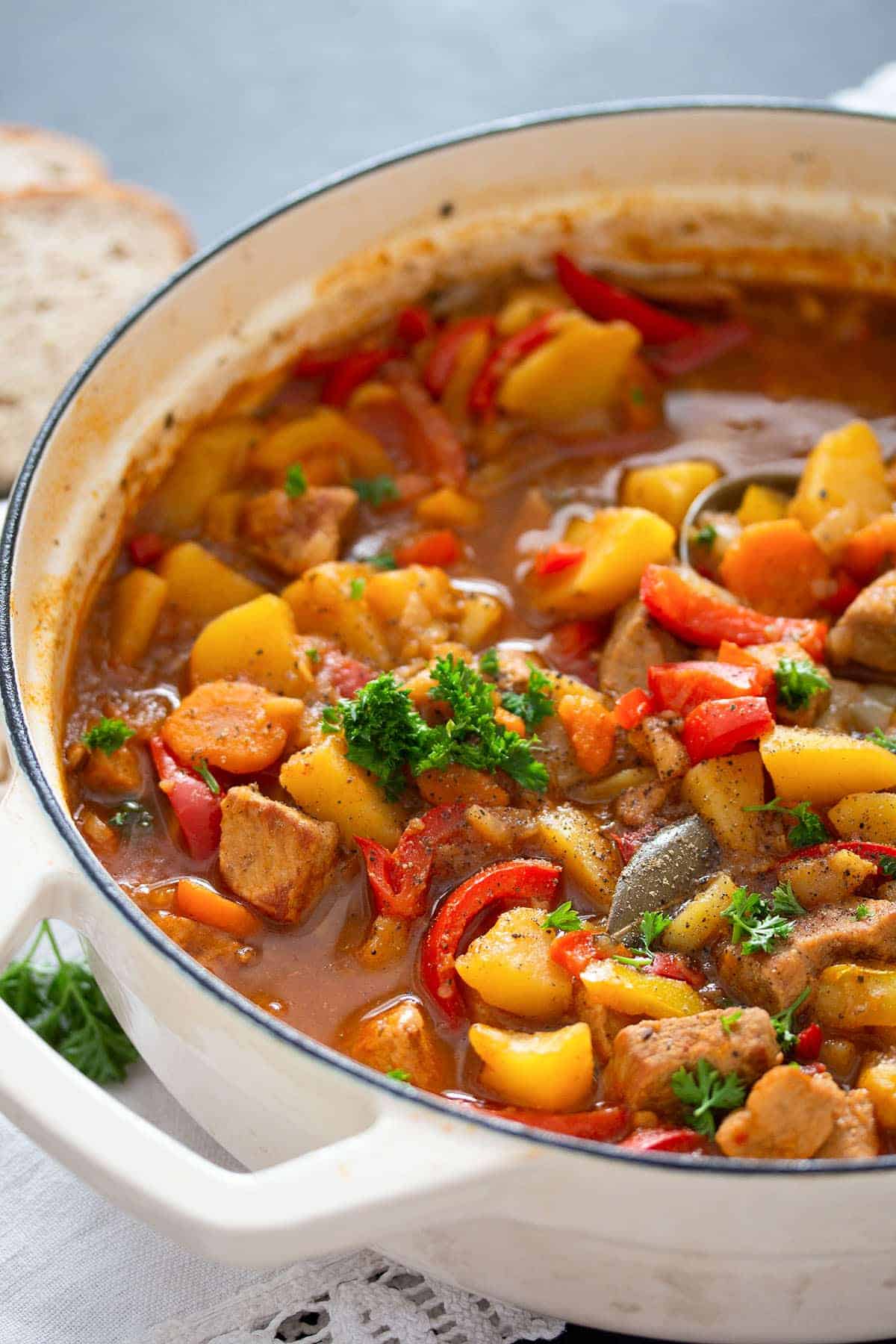 Potato and pork stew in a white large pot.