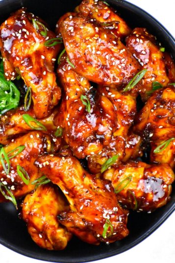 Spicy Korean Wings tossed with a spicy sauce in a black bowl.