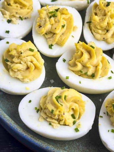 Truffled deviled eggs on a plate with chive garnish.