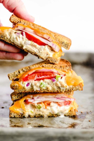 A stack of tuna melt sandwiches on a sheet pan.