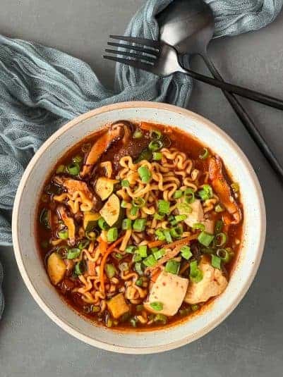 A bowl of ramen noodle soup with veggies and tofu.