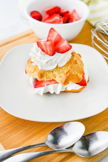 Strawberry shortcake served on a white plate with whipped cream.