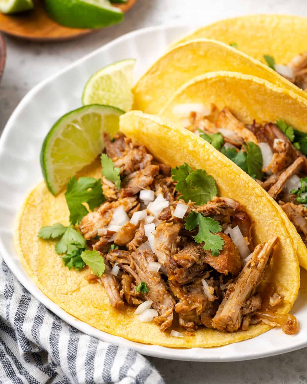 Carnitas tacos served on a white plate.