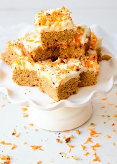 Carrot cake blondies squares on a white cake stand.