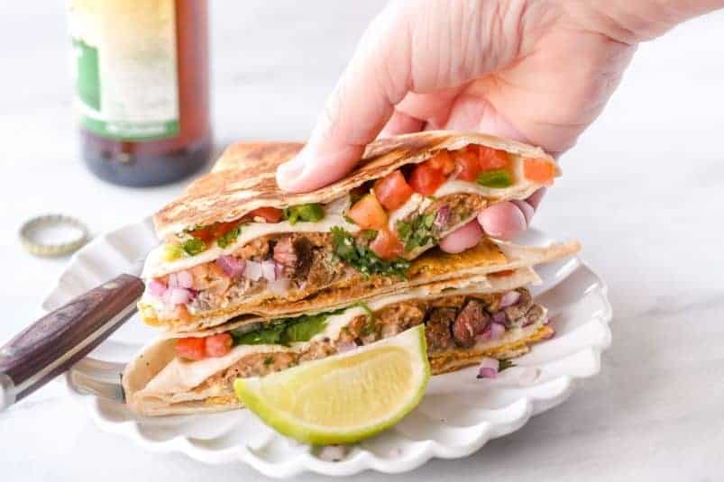 Steak taco crunch wrap, on a plate with lime wedge.