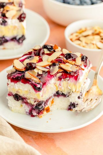 Close up of a slice of blueberry heaven on earth cake with a bite taken out of it.