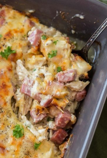 Keto Chicken Cordon Bleu Casserole in a black casserole dish with parsley and a spoon.