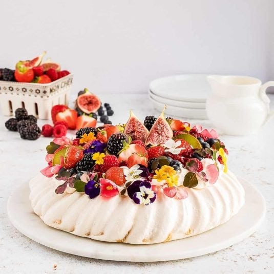 A pavlova topped with berries and figs.