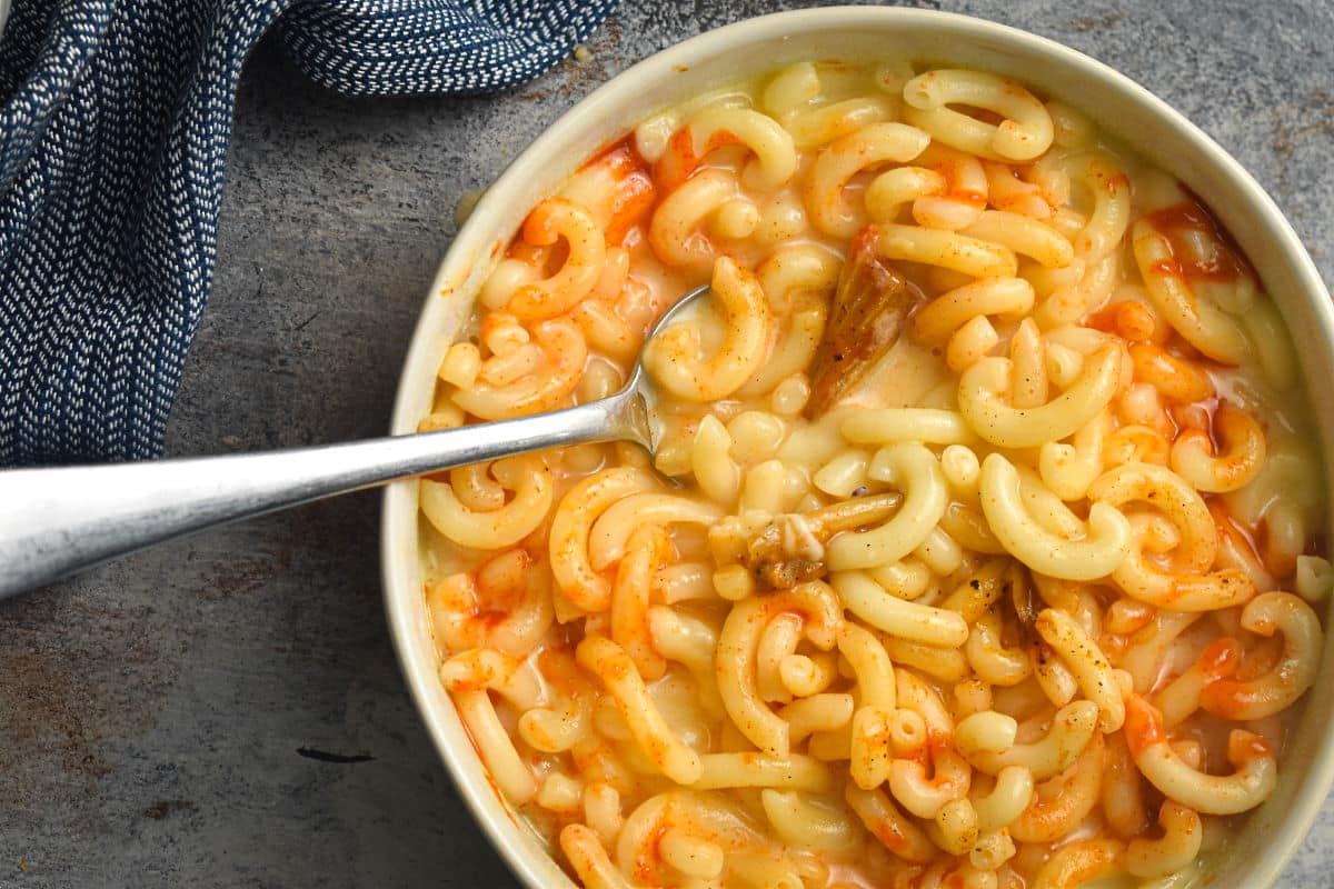 Kimchi mac and cheese in a white bowl with a spoon.