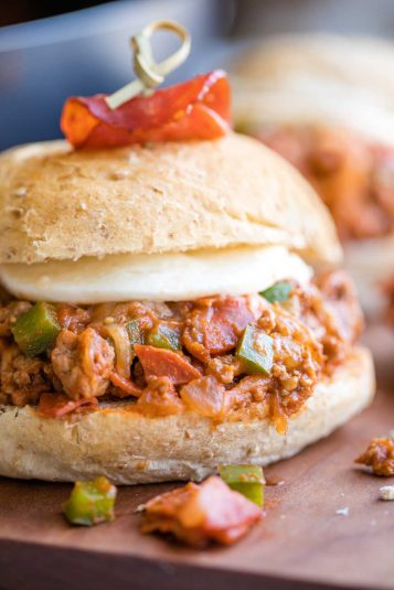 Side view of one pizza sloppy joe with a rolled pepperoni skewered into the top bun.