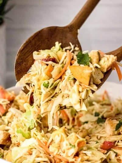 Closed up of Thai chicken salad with peanut dressing being served with wooden spoons.