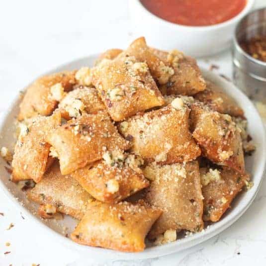 Air fryer pizza rolls in garlic parmesan butter on a plate.