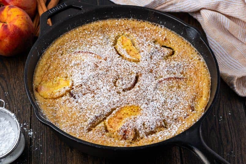 A peach clafoutis in a cast iron skillet on the table.