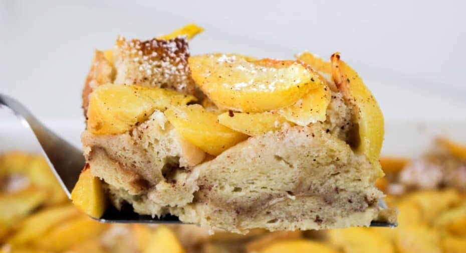 Slice of peach cobbler french toast held in the air on a spatula.