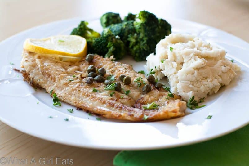 Dover Sole on a white plate with mashed potatoes and broccoli.
