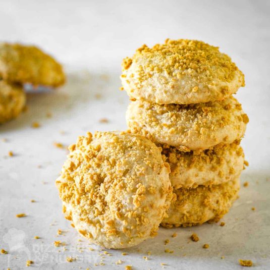 Side shot of five banana cookies stacked together on a grey surface.