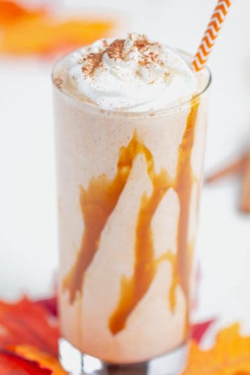 Pumpkin spice latte smoothie in a glass with whipped cream and cinnamon, perfect fall drink.