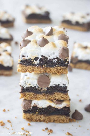 S'mores bars stacked on top of each other, featuring gooey marshmallows, chewy brownies, and a graham cracker crust.