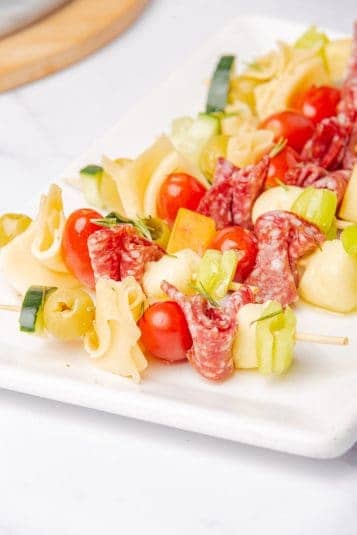 A side angle of antipasto skewers arranged neatly on a white tray.