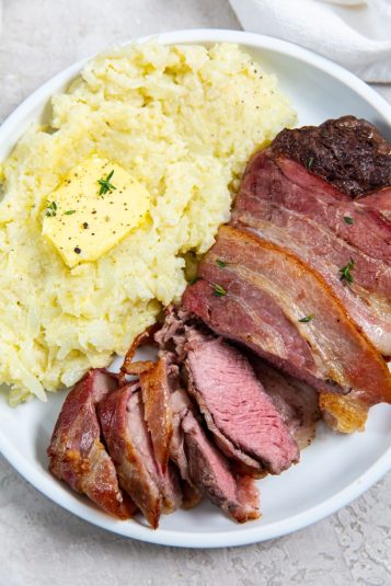 Air Fryer Bacon Wrapped Ribeye Steak with rice, butter and thyme on a white plate.