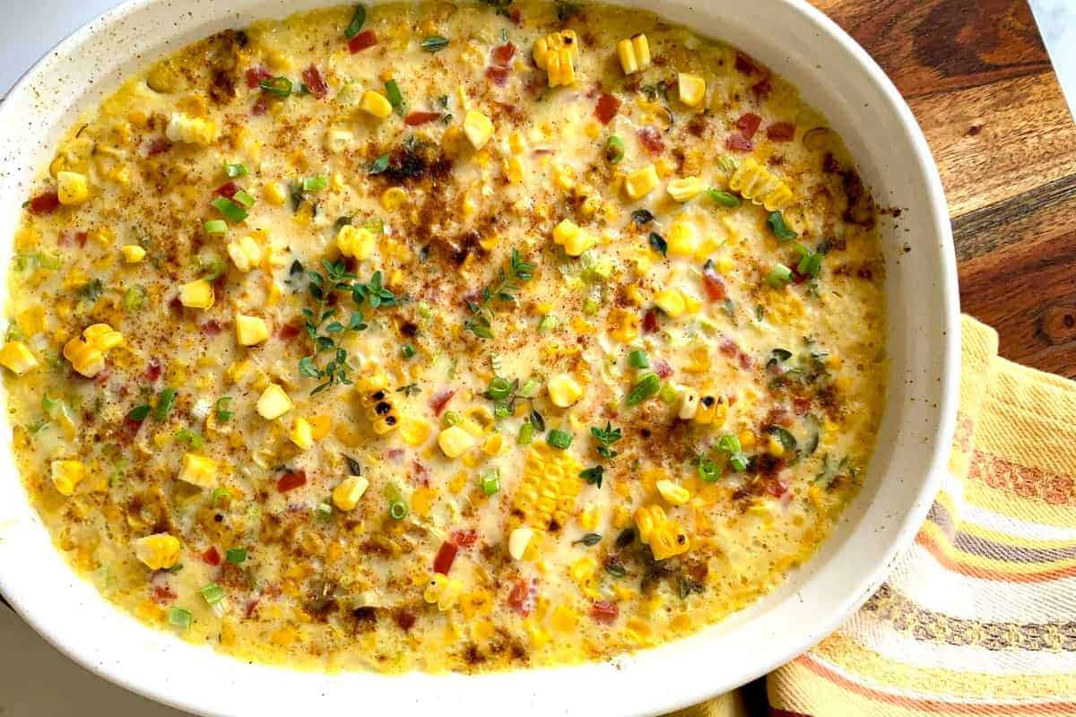 A bowl of mashed potatoes with melted butter, chopped chives, and a spoon.
