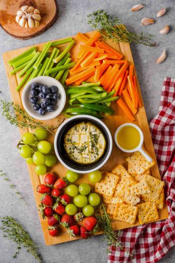 A top down view of a cheese platter with garlic and herb baked brie in the centre.